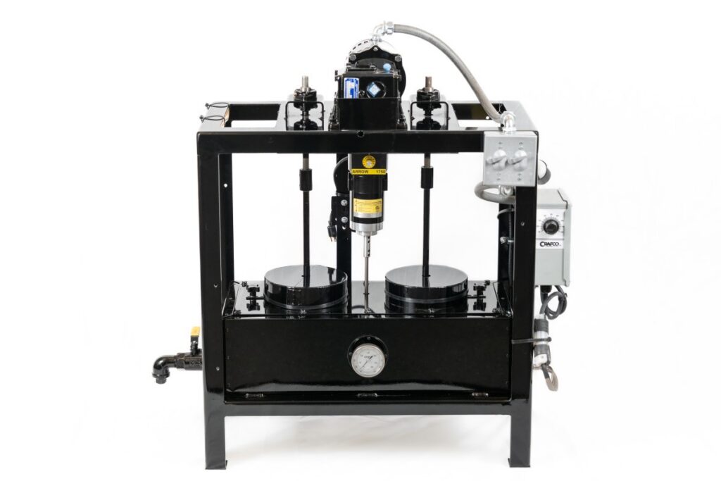 A square frame painted black, consisting of a rectangular enclosed box at the bottom and motors at the top, with spindles extending down into the box. There are gray control panels on the right side and a pour spout on the left side.