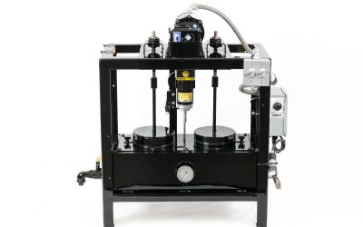 A square frame painted black, consisting of a rectangular enclosed box at the bottom and motors at the top, with spindles extending down into the box. There are gray control panels on the right side and a pour spout on the left side.
