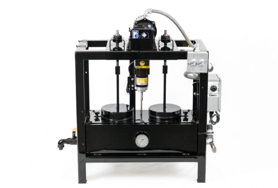 A square frame painted black, consisting of a rectangular enclosed box at the bottom and motors at the top, with spindles extending down into the box. There are gray control panels on the right side and a pour spout on the left side.